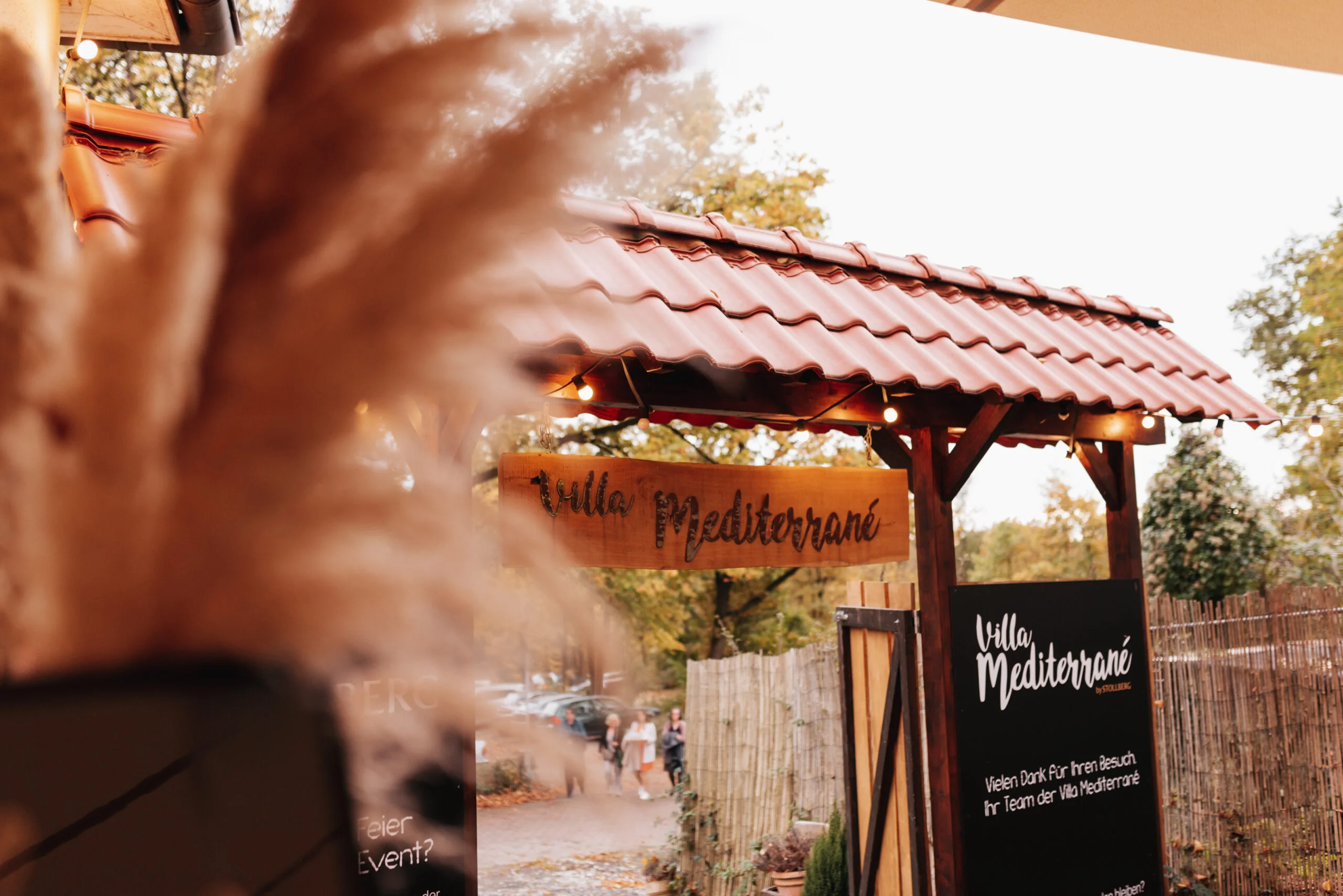 Eingangstor der Villa Mediterrane in Bielefeld mit Holzüberdachung und Schild