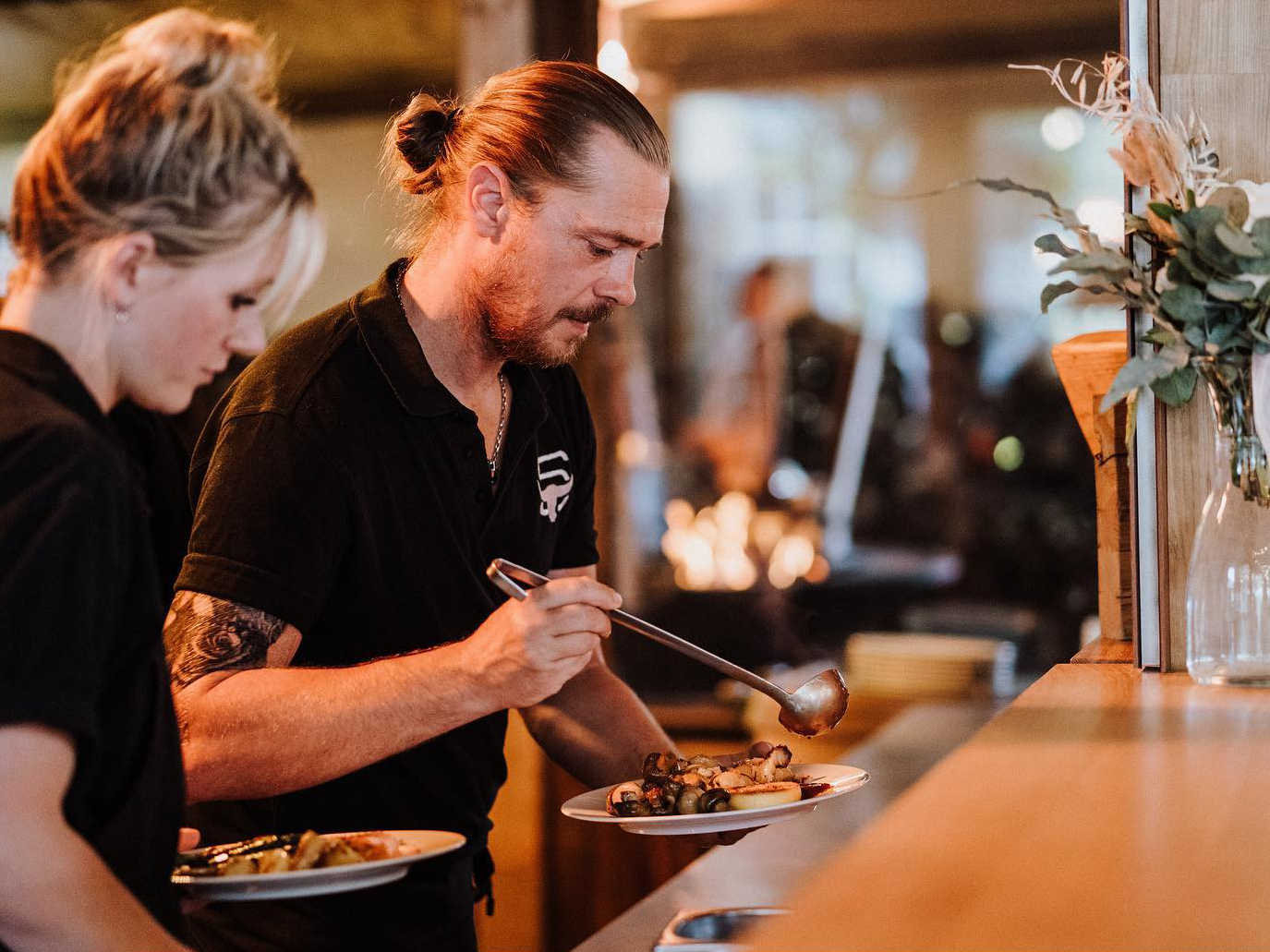 Servicekraft richtet Teller mit warmen Speisen in der Villa Mediterrane an